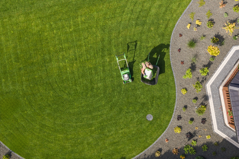A,Person,Is,Mowing,A,Vibrant,Green,Lawn,Surrounded,By Landscaper doing landscaping in Harlow